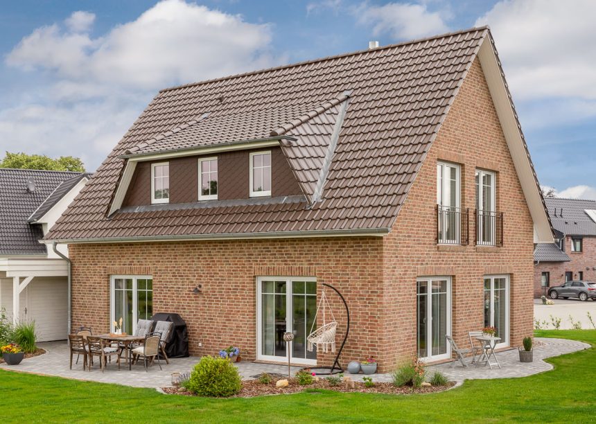 Vooraanzicht van een kapiteinswoning met FD-dakpan J11v in donkerbruin met zicht op het terras.
