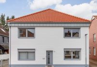 Vooraanzicht van een vrijstaand huis bedekt met moderne dakpan J160 in oudrood