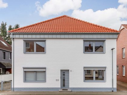 Vooraanzicht van een vrijstaand huis bedekt met moderne dakpan J160 in oudrood
