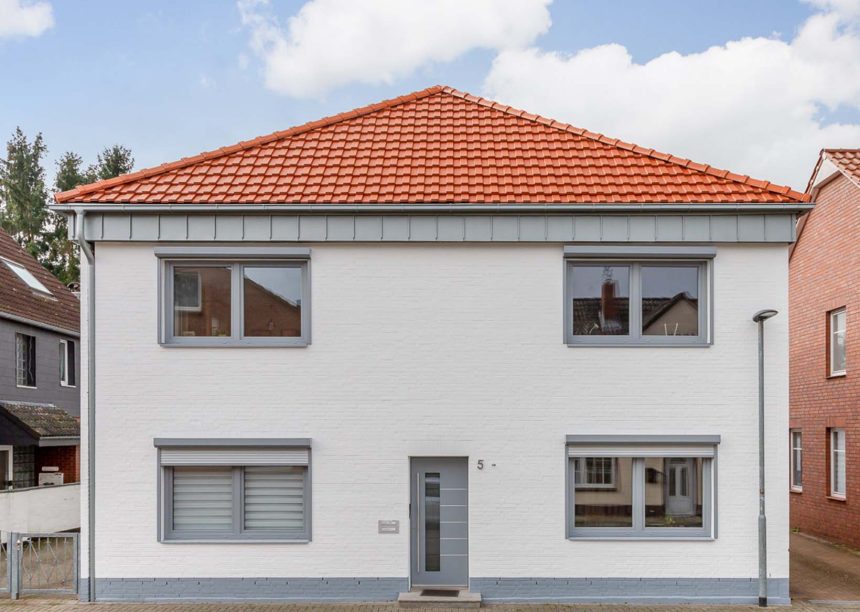 Vooraanzicht van een vrijstaand huis bedekt met moderne dakpan J160 in oudrood
