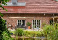 Omgebouwde schuur als gezellige woning met de klassieker J11v in de edel-engobe edelkoper met tuinzicht.