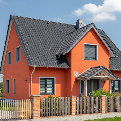 Einfamilienhaus mit orangener Fassade und schwarzem Dach