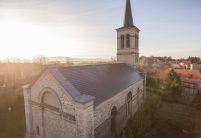 Historische kerk met minimalistische dakpan in edelschiefer vanuit vogelperspectief.