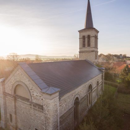 Historische kerk met minimalistische dakpan in edelschiefer vanuit vogelperspectief.