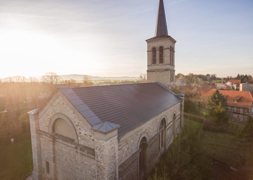 Historische kerk met minimalistische dakpan in edelschiefer vanuit vogelperspectief.