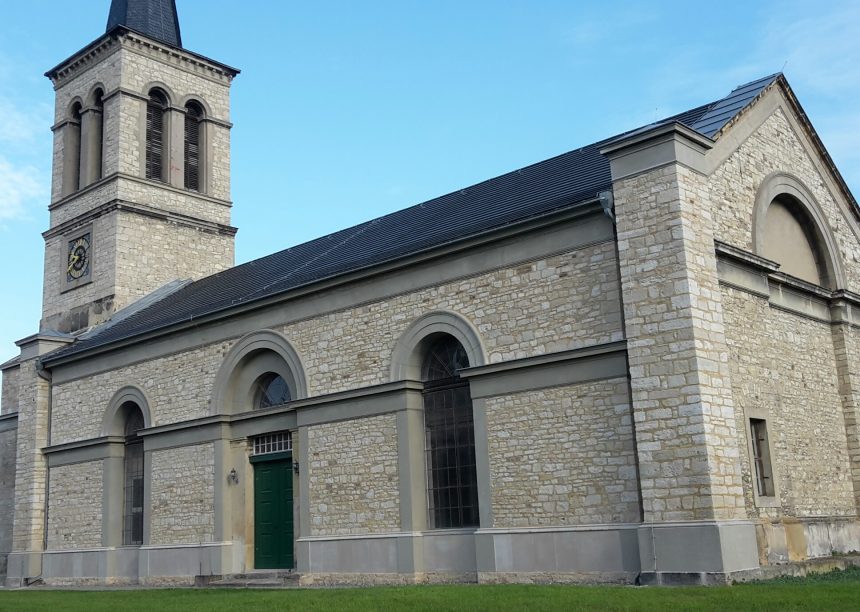 Historische kerk met minimalistische dakpan in edelschiefer vanuit vogelperspectief.