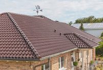 Stijlvolle bungalow met kastanjebruine dakpannen op het schilddak in schuin dakzicht.