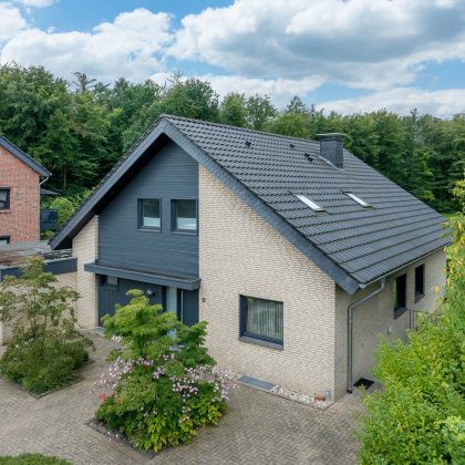 Gerenoveerd bakstenen huis met klassieke J11v in modern oud zwart op het schuine dak in het bovenaanzicht vanuit de lucht