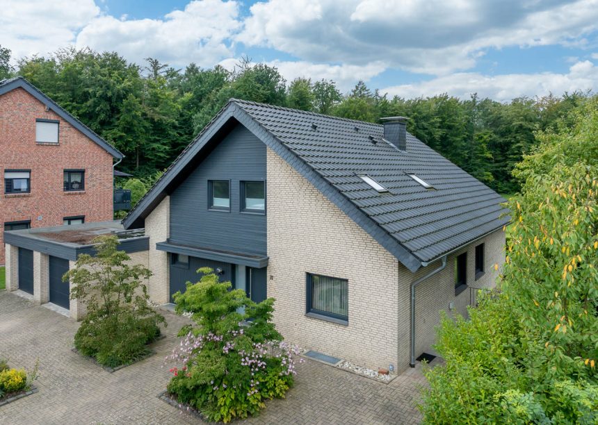 Gerenoveerd bakstenen huis met klassieke J11v in modern oud zwart op het schuine dak in het bovenaanzicht vanuit de lucht