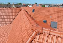 Appartementengebouw met de keramische dakpan Tradition van Jacobi in roodbruin. Op deze foto staat de hoekkeperspits met de Tradition-nokvorsten centraal.