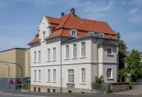 De dakpan Tradition in roodbruin op een stedelijk appartementencomplex – de keramische dakpan van Jacobi met het karakteristieke dubbelholle profiel. Hier uitgevoerd in roodbruin.
