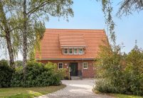 Frontaal gefotografeerd: jeugdcentrum met de keramische dakpan Dubbele Holle Dakpan Z2 in natuurrood, een gevel in metselbaksteen en een zadeldak.