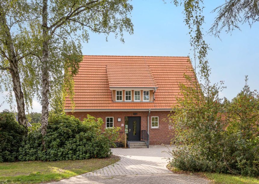 Frontaal gefotografeerd: jeugdcentrum met de keramische dakpan Dubbele Holle Dakpan Z2 in natuurrood, een gevel in metselbaksteen en een zadeldak.