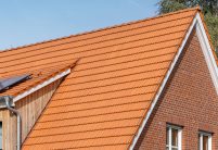 Geveltop van een jeugdcentrum met de keramische Dubbele Holle Dakpan Z2 in natuurrood. Op de foto staan de beginvorst, de linker- en rechtergevelpan en de bakstenen gevel centraal.