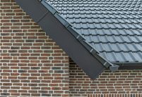 Inspirerende referentie voor bouwers en ontwerpers met J11v in spacegrijs op een zadeldak, met focus op de zijafwerking van het dak bij de gevelrand.