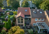 PV-oplossing met zonnepannen in roodbruin – het volledige referentieproject van een hoekrijwoning, gefotografeerd met een drone.